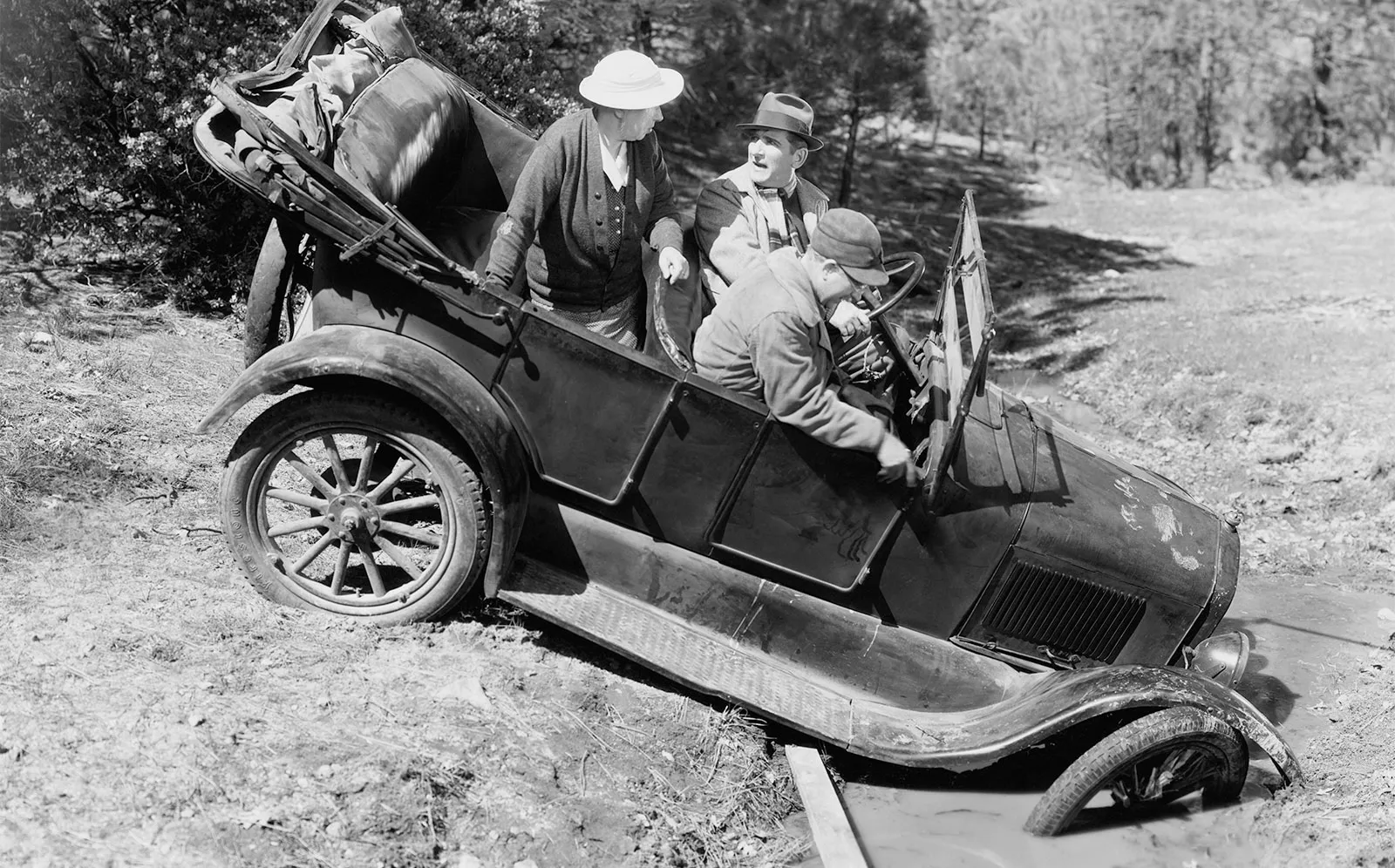 Humorous black and white image of vintage car stuck in ditch.
